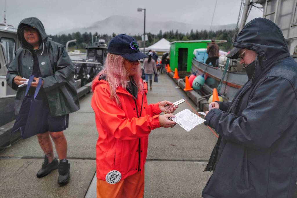 Cheri Wharton validates Jeremy Dunns tickets at the Don D. Statter Boat Harbor in Auke Bay at the start of the Golden North Salmon Derby on Friday, Aug. 23, 2019. (Michael Penn | Juneau Empire)