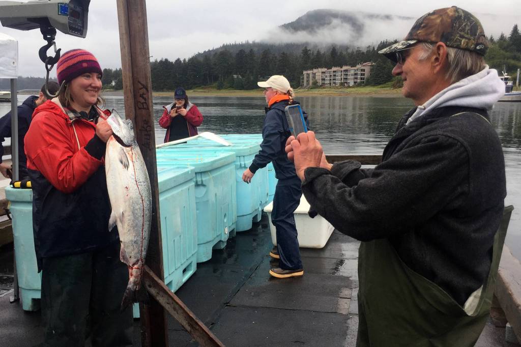 Monika Walker, 36, poses with her her 20.7-pound king salmon as her father Mike Bethers snaps a photo at Don D. Statter Harbor in Auke Bay on Friday, Aug. 23, 2019. (Nolin Ainsworth | Juneau Empire)
