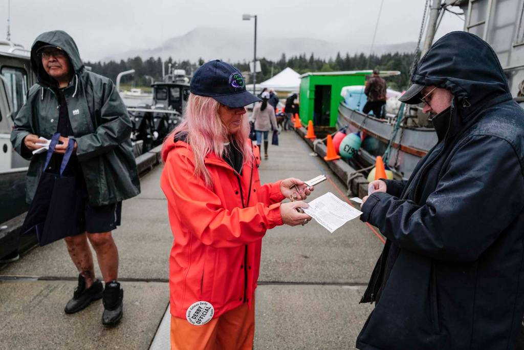 Derby Official Cheri Wharton validates Jeremy Dunns ticket at the Don D. Statter Boat Harbor in Auke Bay at the start of the Golden North Salmon Derby on Friday, Aug. 23, 2019. (Michael Penn | Juneau Empire)