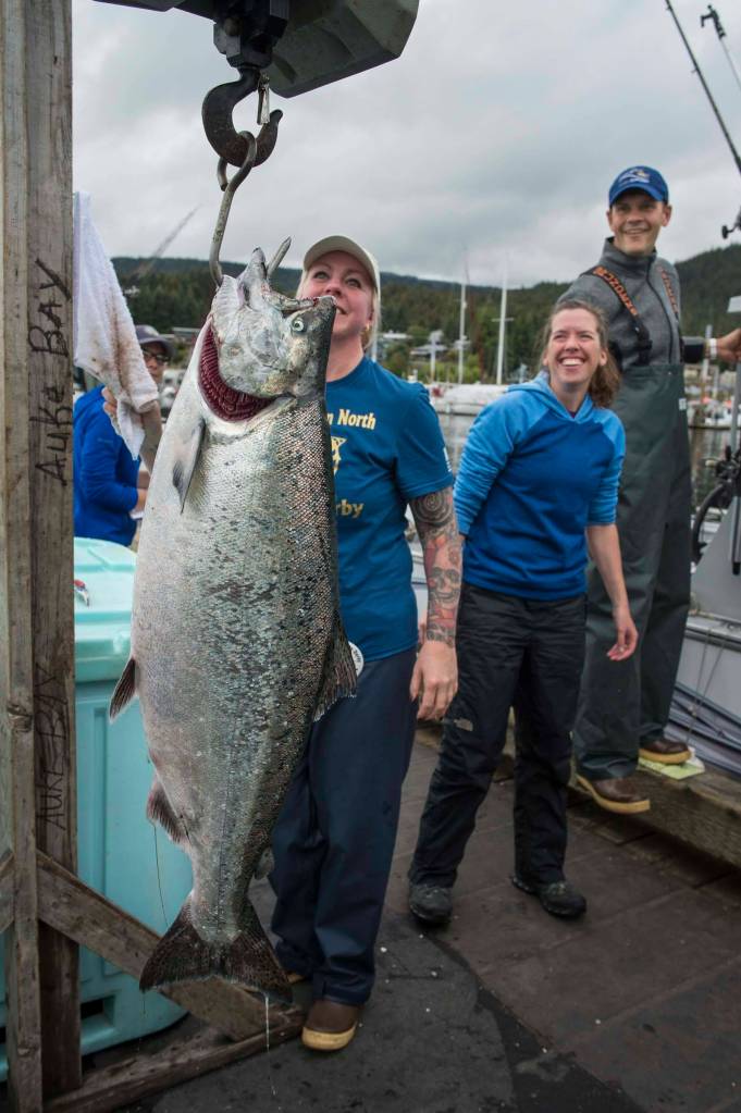 Sadie Wright, center, and Chris Krenz, right, watch as volunteer Kami Bartness weights Wrights king salmon at the Golden North Salmon Derbys station at the Don D. Statter Memorial Boat Harbor on Saturday, Aug. 24, 2019. The fish weighted in at 20.1 pounds. (Michael Penn | Juneau Empire)