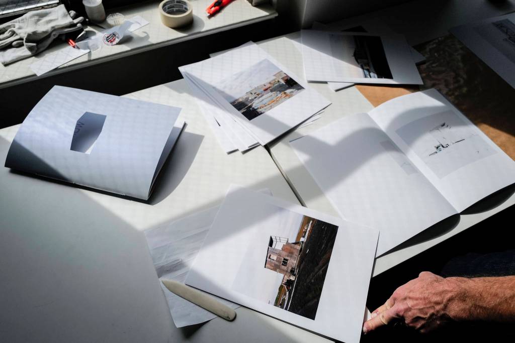 Seattle-based photographer Eirik Johnson works with Ben Huff, a local photographer and editor of Ice Fog Press, on a hand-made book of Johnsons photographs titled Barrow Cabins on Wednesday, Aug. 21, 2019. (Michael Penn | Juneau Empire)