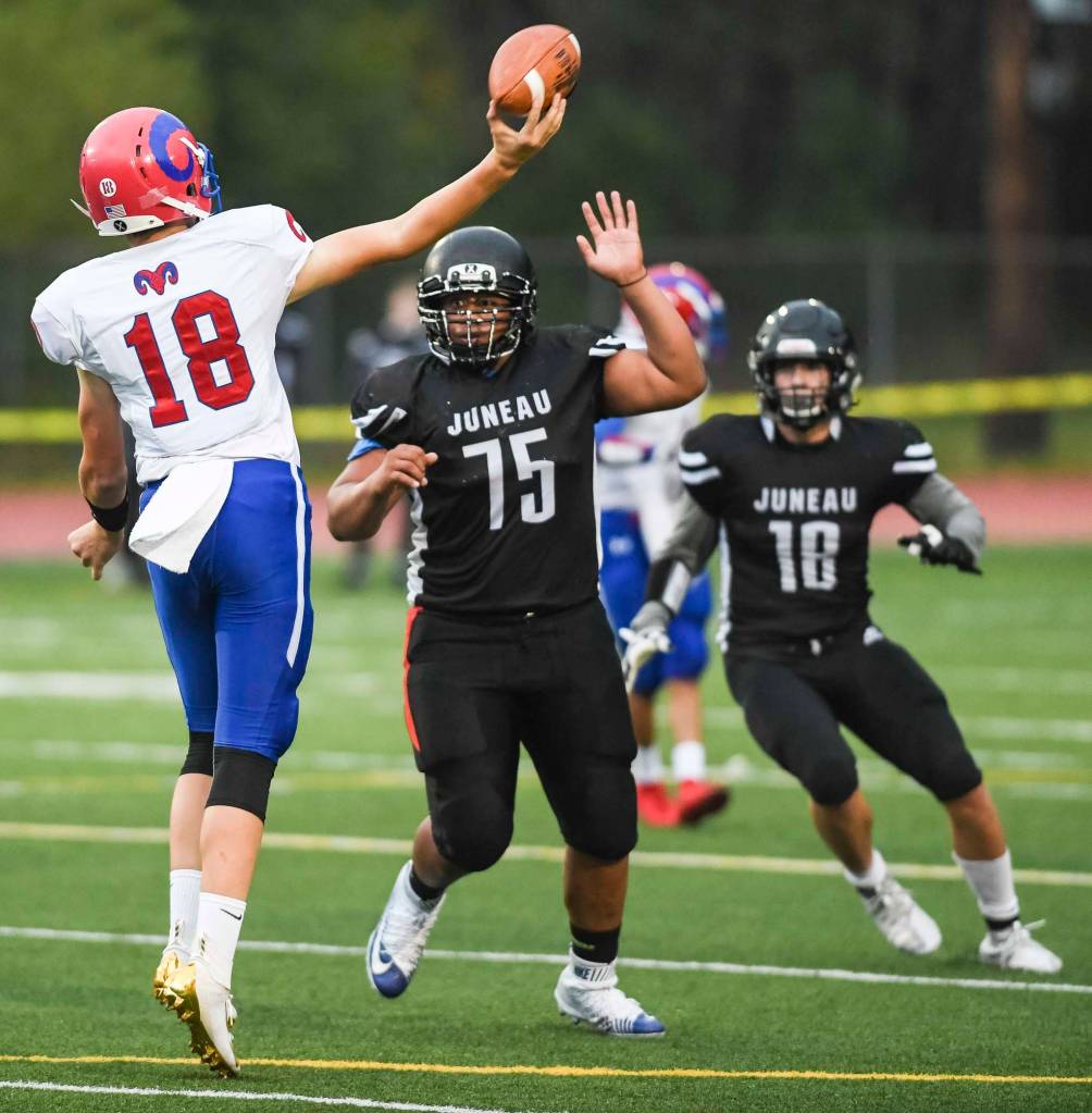 Juneaus Sam Sika, center, pressures Antelope Unions quarterback Trey Hohlbein in the second quarter at Adair-Kennedy Memorial Field on Saturday, Aug. 24, 2019. Juneau won 56-18. (Michael Penn | Juneau Empire)