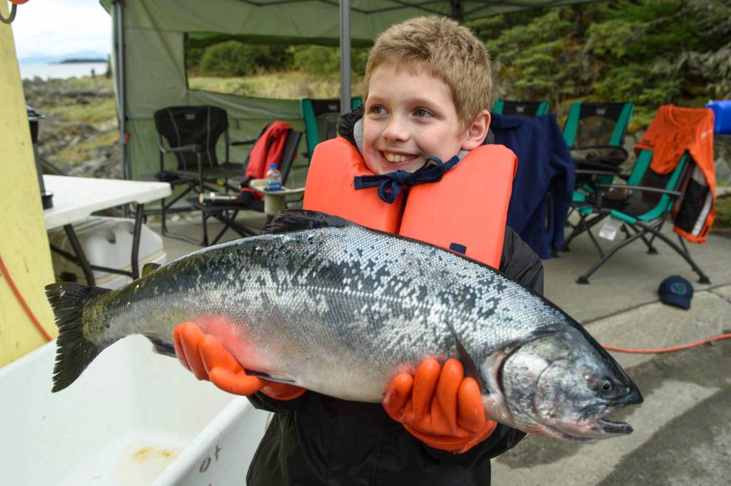 Tito Ritter, 9, holds an 8.5 pound coho he turned in at the Golden North Salmon Derbys station at Amalga Harbor on Saturday. (Michael Penn | Juneau Empire)