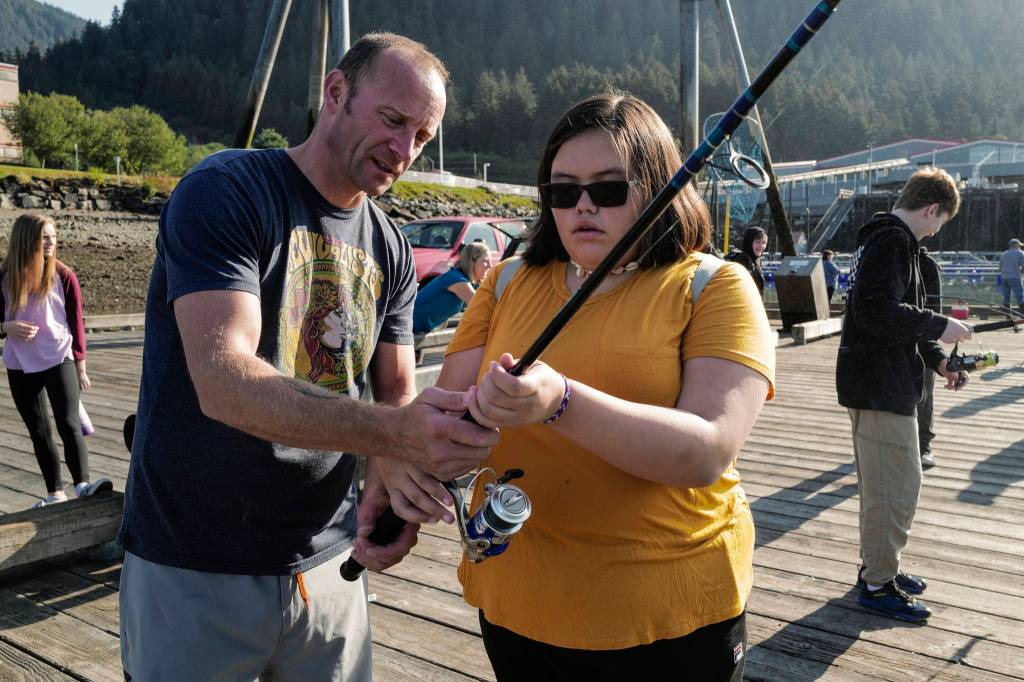 Dzantaki Heeni Middle School eighth-grader Jaylynn Martin, right, is helped by Teacher Bobby Jones while fishing for salmon at the Wayside Park on Channel Drive on Friday, Aug. 30, 2019. The fish will be used in a dog treat business the students are developing to raise money for a water filtering system to be used at the school. Two math teachers, Jones and Tennie Bentz, are having the students start four businesses as a way of teaching the use of math in the real world. (Michael Penn | Juneau Empire)