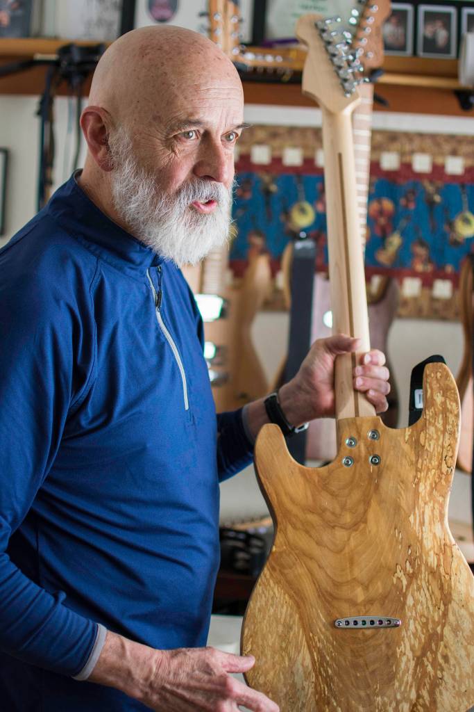 Local guitar maker George Gress holds a solid body electric guitar he made from repurposed wood at his home in March 2018. Gress will be part of this First Friday, Sept. 6. (Michael Penn | Juneau Empire File)