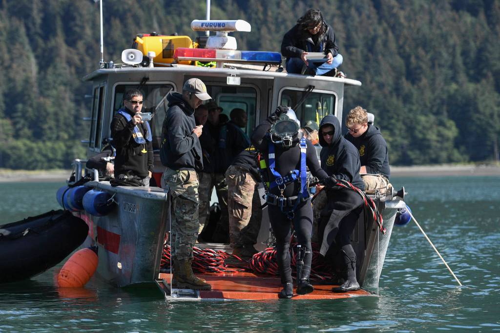 Spc. James Lewis, center, steps off the bow of a Juneau Harbormasters boat as members of the Armys 74th Engineer Dive Detachment work to retrieve lost crab pots in Gastineau Channel for the Douglas Indian Association/NOAA Marine Debris Project on Thursday, Sept. 5, 2019. The project aims to identify and remove derelict crab pots and their continued negative impact on wildlife and the environment. (Michael Penn | Juneau Empire)