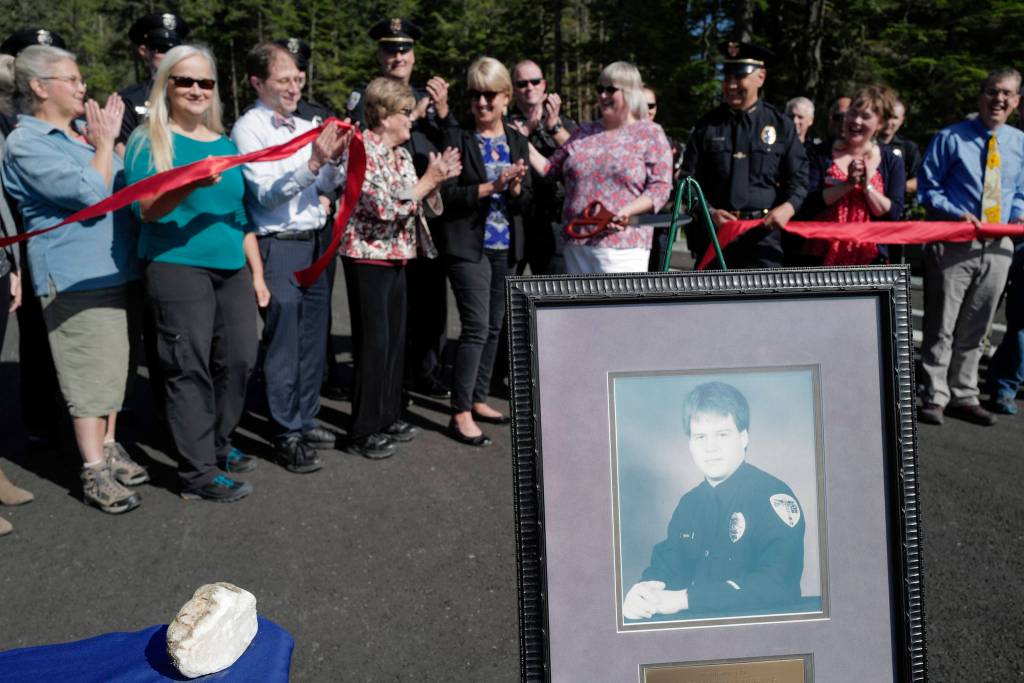 City and state officals attend a ribbon-cutting ceremony on Karl Reishus Boulevard to commemorate the near completion of the Pederson Hill Subdivision on Friday, Sept. 6, 2019. Reishus, pictured, was a Juneau Police Department officer who died in 1992 when he fell from a 40-foot tower during a training exercise. (Michael Penn | Juneau Empire)