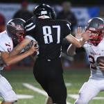 Juneaus Cole Jensen, center, moves to sack Wasilla quarterback Colton Lindquist, right, despite blocking by Wasillas Andrew Devine in the second quarter at Adair-Kennedy Memorial Field on Friday, Sept. 6, 2019. Juneau won 63-0. (Michael Penn | Juneau Empire)