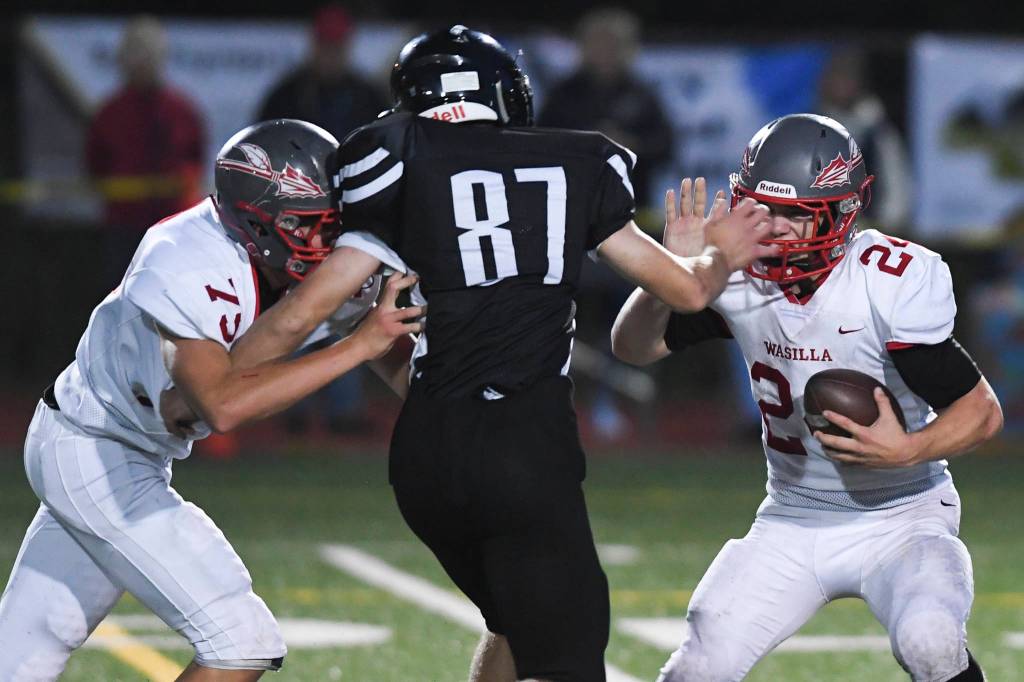Juneaus Cole Jensen, center, moves to sack Wasilla quarterback Colton Lindquist, right, despite blocking by Wasillas Andrew Devine in the second quarter at Adair-Kennedy Memorial Field on Friday, Sept. 6, 2019. Juneau won 63-0. (Michael Penn | Juneau Empire)