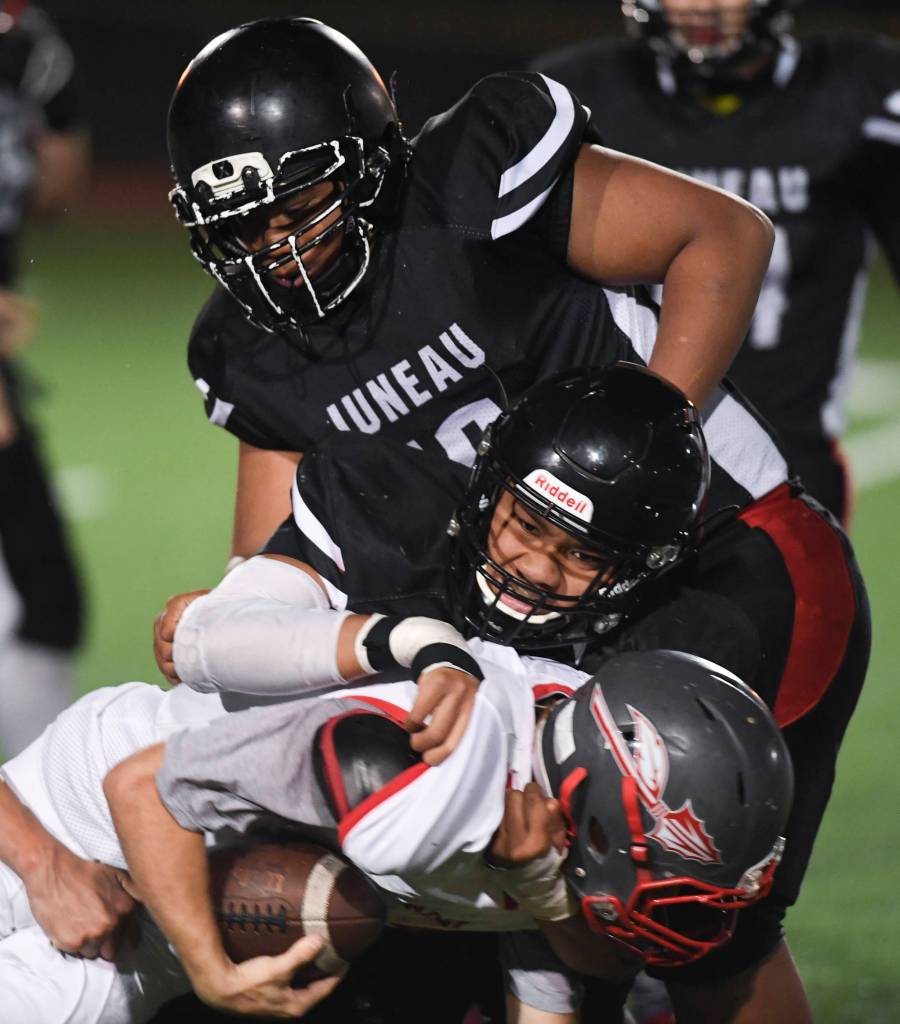 Juneaus Meki Toutaiolepo, center, tackles Wasillas Hunter Hayes in the third quarter at Adair-Kennedy Memorial Field on Friday, Sept. 6, 2019. Juneau won 63-0. (Michael Penn | Juneau Empire)