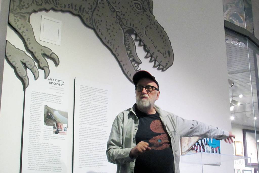 Artist Ray Troll, seen in this May 2019 photo standing under the jaws of a dinosaur thats part of the Cruisin the Fossil Coastline exhibit, will be present for an event at the Juneau Arts & Culture Center Sunday, Sept. 22, 2019. (Ben Hohenstatt | Juneau Empire File)