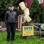 Juneau artist Arnie Weimer stands next to his bucket sculpture and a pro-JACC sign in front of his 12th Street home on Friday, Sept. 20, 2019. (Michael Penn | Juneau Empire)