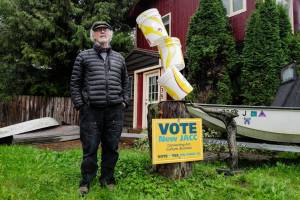 Juneau Artist Arnie Weimer stands next to his bucket sculpture and a pro-JACC sign in front of his 12th Street home on Friday, Sept. 20, 2019. (Michael Penn | Juneau Empire)