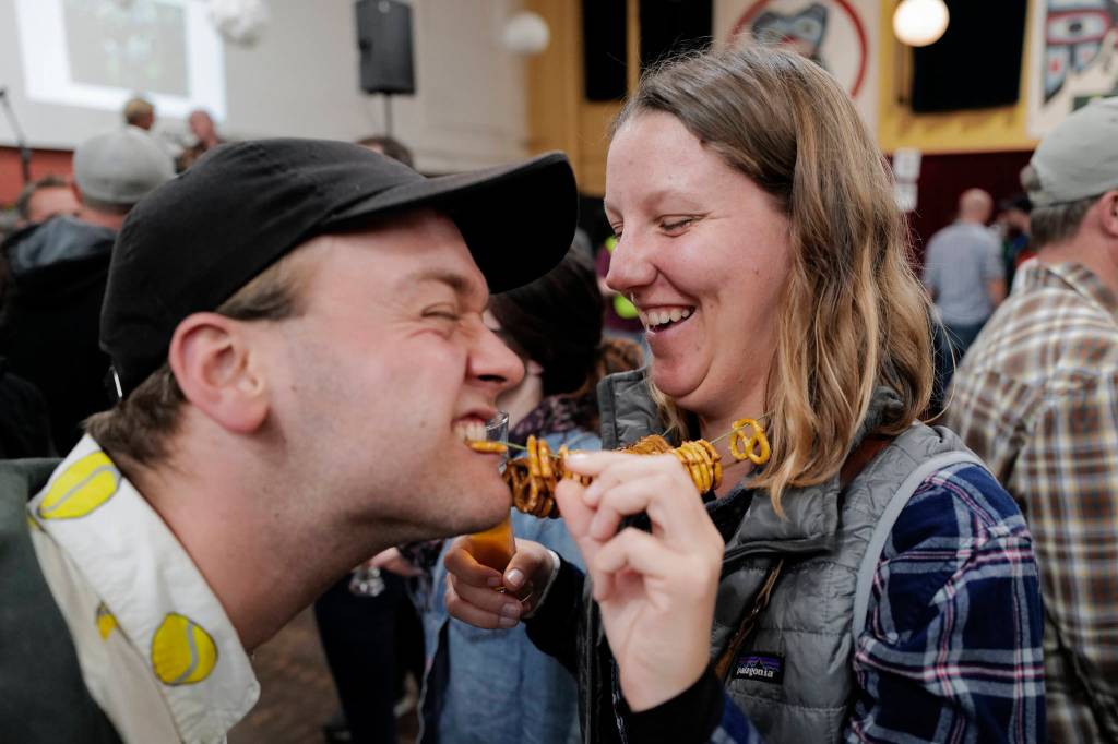 Griffin Bailey, left, takes a bite from Annie Goodenoughs pretzel necklace the Rotary Club of Juneaus 8th Annual Capital Brewfest at the Juneau Arts and Culture Center on Saturday, Sept. 21, 2019. Twenty brewing and distribution companies were on hand for the fundraiser to benefit the University of Alaska and Rotarys service projects, scholarships, international youth exchanges and other project. The event was sold out with 900 tickets sold. (Michael Penn | Juneau Empire)