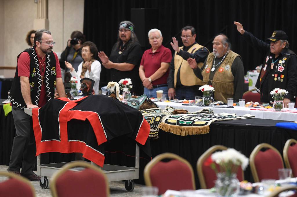 Eric Hollinger, Tribal Liaison for the Repatriation Office of the Smithsonians National Museum of Natural History, left, pushes in a cart holding the original sculpin clan hat for a welcoming ceremony at Elizabeth Peratrovich Hall on Wednesday, Sept. 25, 2019. The hat was collected from the Kiks.ádi clan in Sitka in 1884. The Smithsonian Institution used a 3D digitization process to document the hat and constructed a replica hat using traditional materials. (Michael Penn | Juneau Empire)