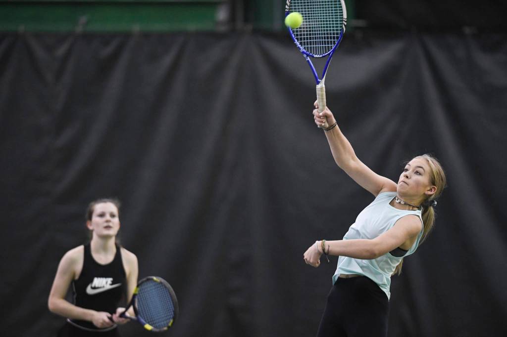 Jaymie Collman hits an overhead as she plays in the girls doubles final with partner Katie Pikul, background, against Adelie McMillan and Olivia Moore during the Region V Tennis Tournament at The Alaska Club/JRC on Saturday, Sept. 28, 2019. McMillan/Moore won 7-6, 6-4. (Michael Penn | Juneau Empire)