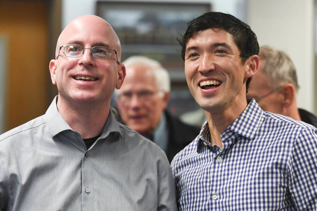 Assembly members Wade Bryson, left, and Greg Smith watch results come in at City Hall on Tuesday, Oct. 1, 2019. (Michael Penn | Juneau Empire)