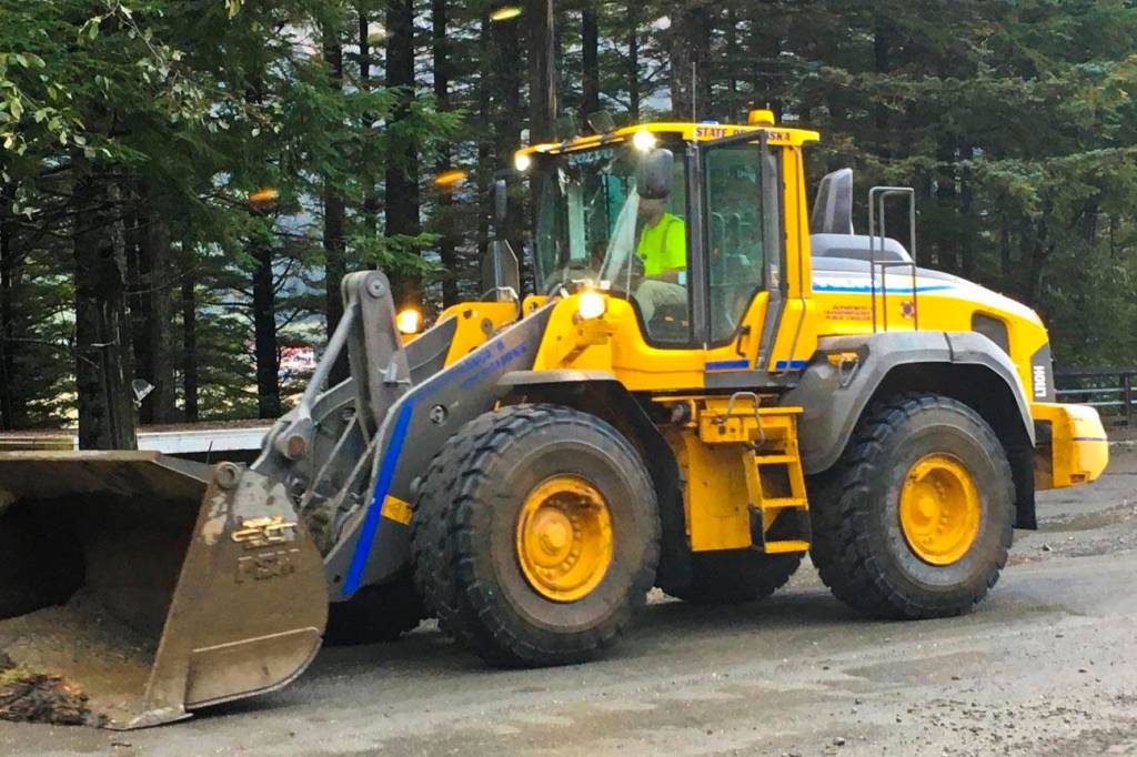 A Department of Transportation employee clears debris off Douglas Highway after heavy rains in Juneau washed out roads, caused mudslides, and damaged houses and vehicles, Oct. 6, 2019. (Michael S. Lockett | Juneau Empire)