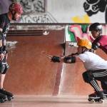 Jennifer Gross, right, and Shabadrang Khalsa, who skate with the Juneau Rollergirls, teach Empire reporter Michael S. Lockett how to rollerskate at the Pipeline Skate Park on Friday, Oct. 11, 2019. (Michael Penn | Juneau Empire)