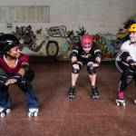 Jennifer Gross, left, and Shabadrang Khalsa, who skate with the Juneau Rollergirls, teach Empire reporter Michael S. Lockett how to rollerskate at the Pipeline Skate Park on Friday, Oct. 11, 2019. (Michael Penn | Juneau Empire)