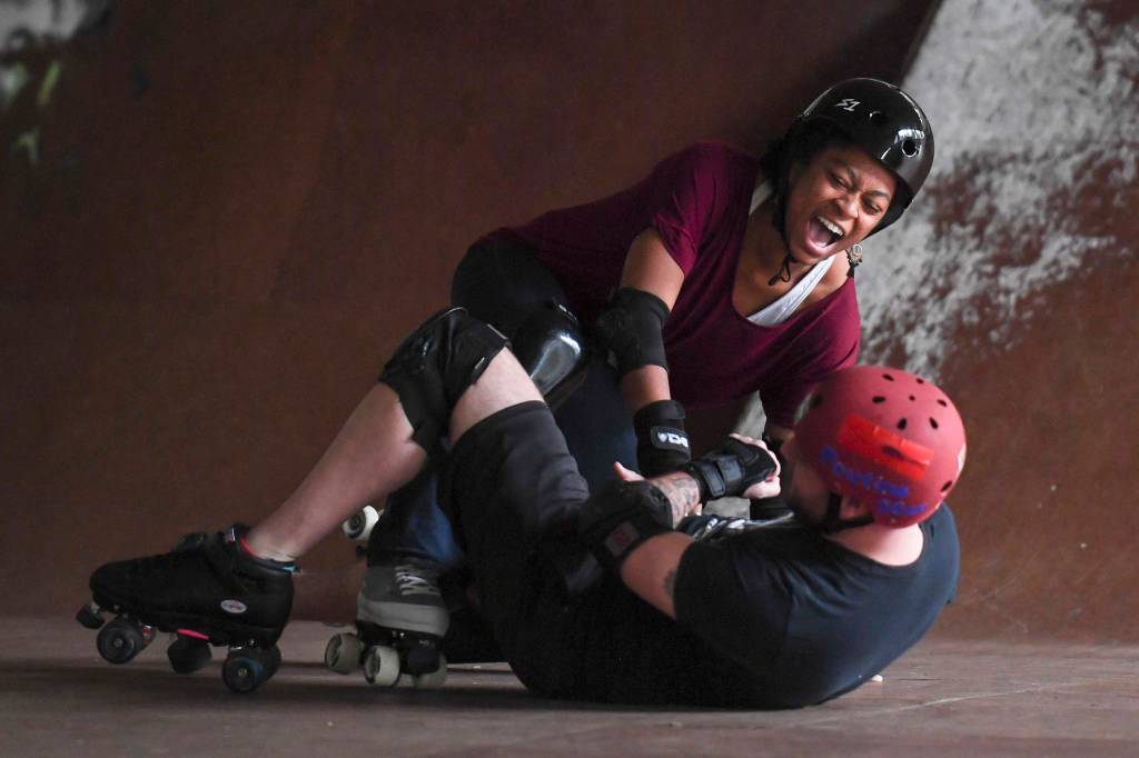 Jennifer Gross gets pulled down as Empire reporter Michael S. Lockett falls at the Pipeline Skate Park on Friday, Oct. 11, 2019. (Michael Penn | Juneau Empire)