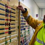 Mark Kiessling, general manger at the Kensington Mine moves a brass tag used to track how many people are currently in the mine on Monday, Oct. 14, 2019. (Peter Segall | Juneau Empire)
