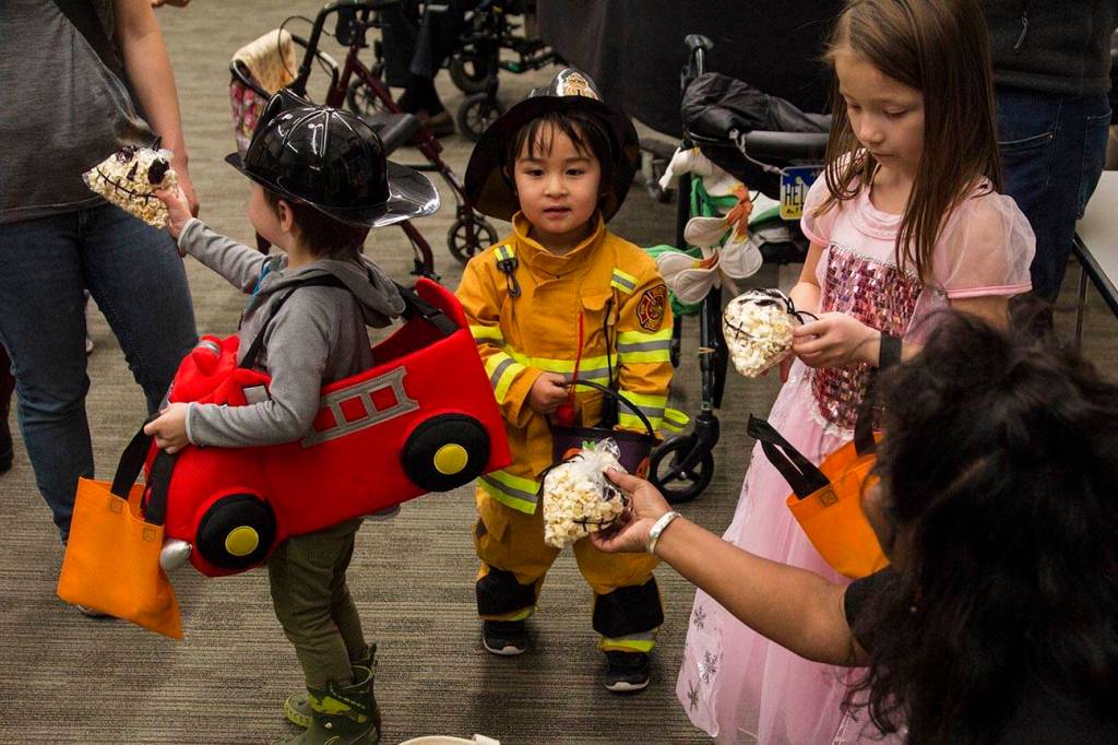 Raineka Ackley, parent educator with Parents as Teachers program, hands a Halloween treat to Denali, 3, as members of the program and children visited Juneau Pioneer Home to have an early Halloween with the residents on Tuesday, Oct. 22, 2019. (Michael S. Lockett | Juneau Empire)