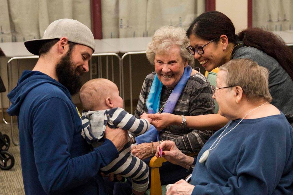 Residents of the Juneau Pioneer Home play with a baby as members of the Parents as Teachers program and a number of children visited to have an early Halloween on Tuesday, Oct. 22, 2019. (Michael S. Lockett | Juneau Empire)