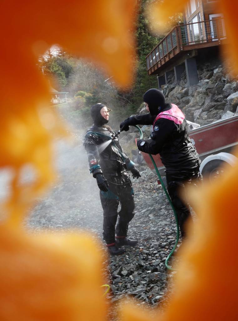 Annie Raymond and Tamsen Peeples rinse off with warm water after carving pumpkins underwater at sixth annual Spooktacular Dive and Underwater Pumpkin Carving event Saturday, Oct. 26, 2019. (Ben Hohenstatt | Juneau Empire)