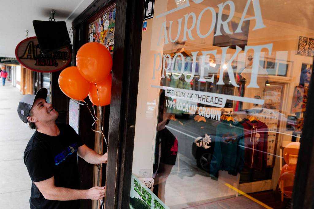 Scott Baxter, owner of Aurora Projekt, puts out balloon for the Trick or Treat Downtown event on Thursday, Oct. 31, 2019. More than 70 business put out orange balloons to participate in the event aimed at young children. (Michael Penn | Juneau Empire)