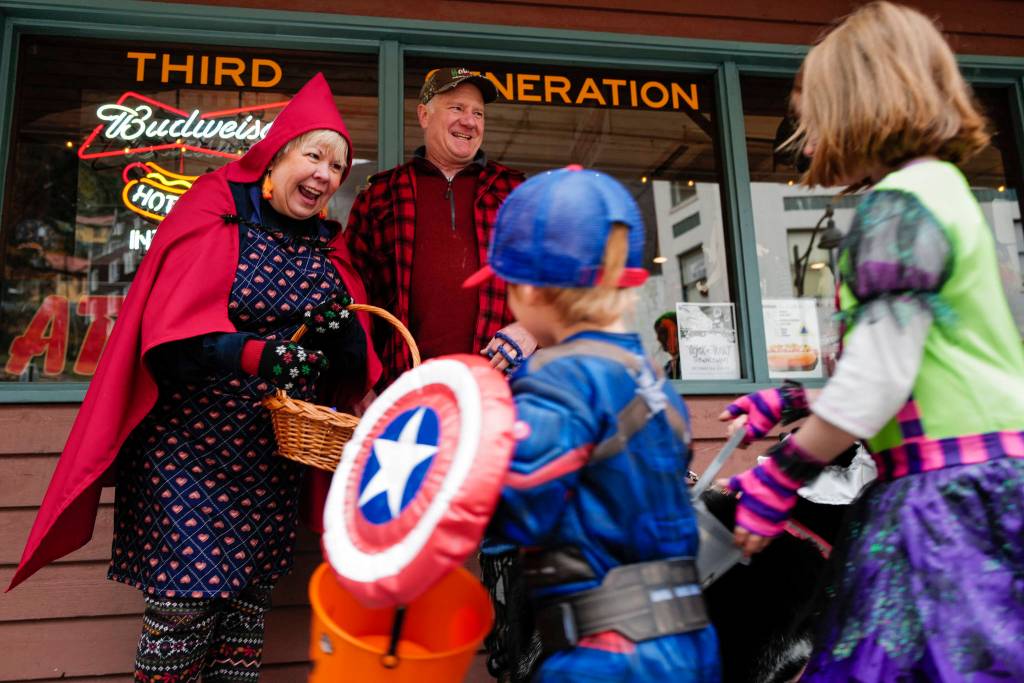 Jewels and Joe Butler greet children in front of the Triangle Bar during the Trick or Treat Downtown event on Thursday, Oct. 31, 2019. More than 70 business put out orange balloons to participate in the event aimed at young children. (Michael Penn | Juneau Empire)