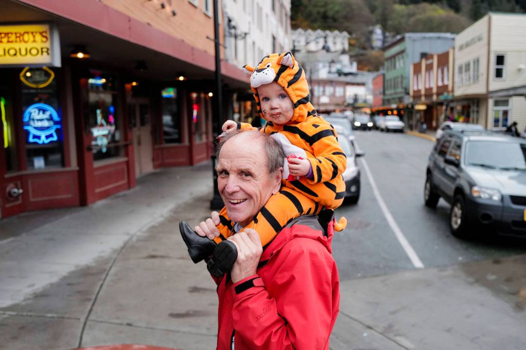 Bruce Denton carries his granddaughter, Hali Hall, 1, during the Trick or Treat Downtown event on Thursday, Oct. 31, 2019. More than 70 business put out orange balloons to participate in the event aimed at young children. (Michael Penn | Juneau Empire)