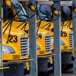 School buses sit idle at the First Student lot on Mendenhall Loop Road in this May 2014 photo. (Michael Penn \ Juneau Empire File)