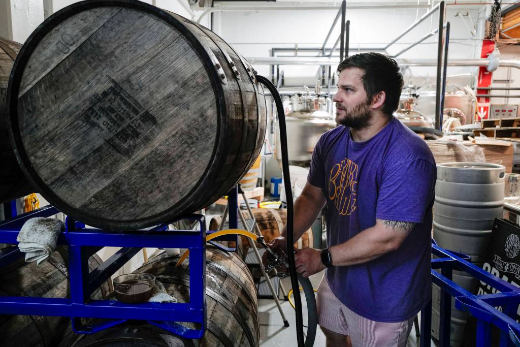 Matt Barnaby, co-owner and brewer at the Barnaby Brewing Company, works to fill wooden casks for a longer term beer project on Wednesday, Nov. 6, 2019. Barnaby has added his name to a list of commenters who dont like a proposed definition change by the Alcoholic Beverage Control Board that would limit the sorts of activities that can happen in breweries and distilleries. (Michael Penn | Juneau Empire)