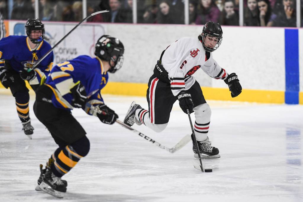 Juneau-Douglas Colter Polley moves the puck against Monroe Catholics Miles Fowler at the Treadwell Arena on Friday, Nov. 15, 2019. JDHS won 10-0. (Michael Penn | Juneau Empire)