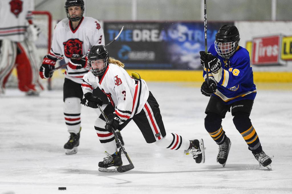 Juneau-Douglas Taylor Bentley moves the puck against Monroe Catholics Dom Coiley at the Treadwell Arena on Friday, Nov. 15, 2019. JDHS won 13-0. (Michael Penn | Juneau Empire)
