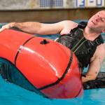 Lt. Cmdr. Scott Shields, a Coast Guard officer stationed in Juneau, flips a small boat during a boating safety training class at the Augustus Brown Swimming Pool on Tuesday, Nov. 19, 2019. The class will qualify the members to teach students around the state about the use and importance of life vests. (Michael Penn | Juneau Empire)