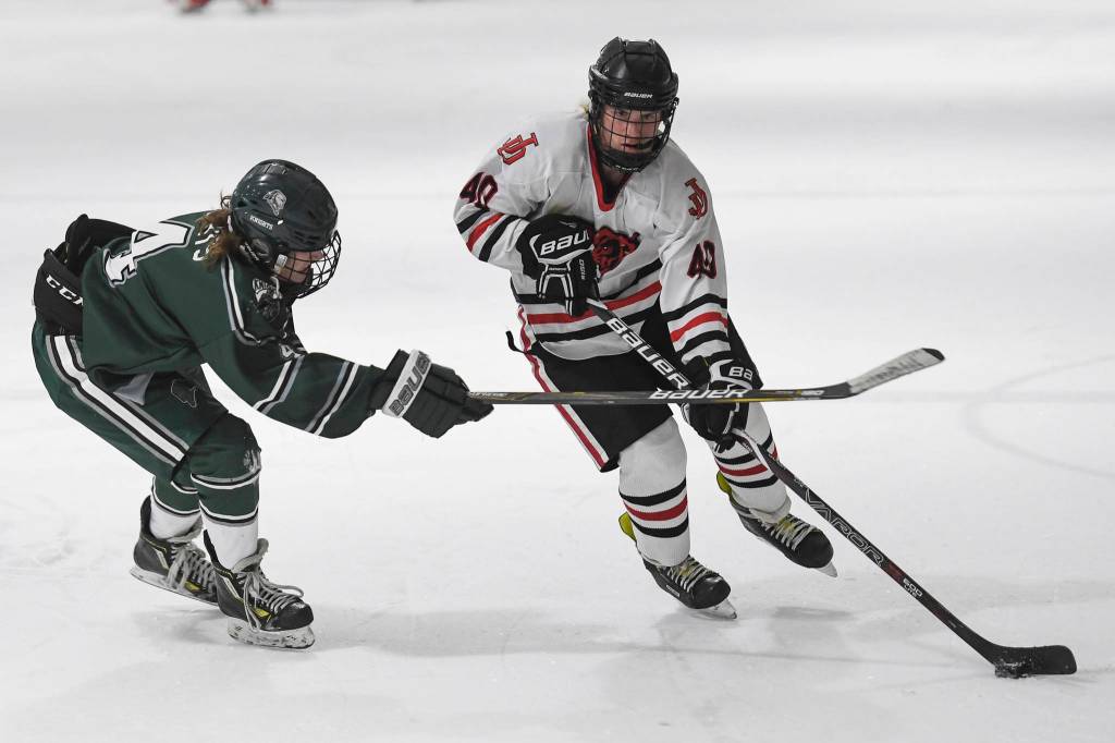 Juneau-Douglas Ethan Welch, right, passes the puck against Colonys Benjamin Loggins at Treadwell Arena on Friday, Nov. 22, 2019. (Michael Penn | Juneau Empire)