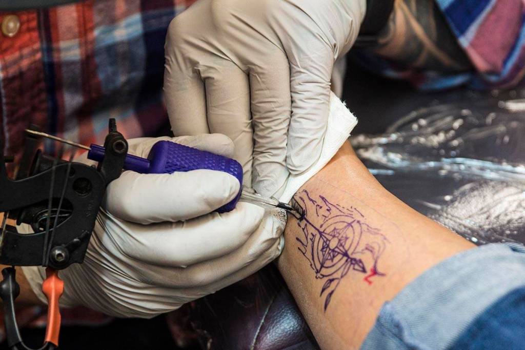 Mario Singh, a tattoo artist, inks one quarter of a group tattoo on Paulette Aceveda during Taku Tattoos International Suicide Survivors Day event on Saturday, Nov. 23, 2019. (Michael S. Lockett | Juneau Empire)