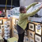 Rebecca Poulson ties up her sign The Outer Coast for her prints at the Public Market in Centennial Hall on Friday, Nov. 23, 2018. (Michael Penn | Juneau Empire File)