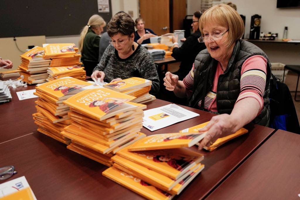 League of Women Voters of Juneau volunteers Karen Crane, left, Cheryl Jebe and others prepare Annie Boochever's book about civil rights leader Elizabeth Peratrovich, "Fighter in Velvet Gloves," for mailing at the Andrew P. Kashevaroff Building on Monday, Dec. 2, 2019. Over 450 copies of the book were packaged to be shipped to libraries and school across Alaska. (Michael Penn | Juneau Empire)