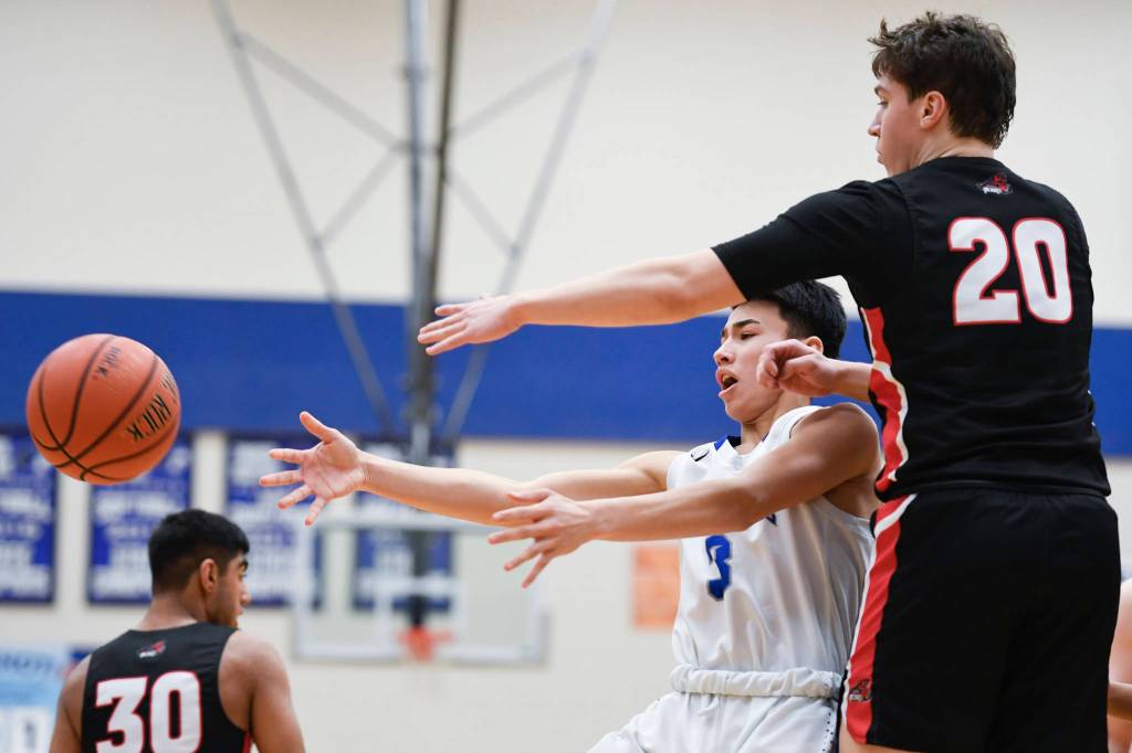 Thunder Mountains Bryson Echiverri passes the ball away from Juneau-Douglas Cooper Kriegmont at TMHS Friday, Feb. 15, 2019. The Thunder Mountain and Juneau-Douglas boys teams will square off Jan. 31, Feb. 1, Feb. 14 and Feb. 15 this season. (Michael Penn | Juneau Empire File)