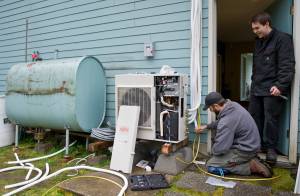 Jake Eames, right, and David Nash install an air-to-air heat pump system to a Mendenhall Valley home Thursday that formerly was using oil for heating in 2015. (Michael Penn | Juneau Empire)