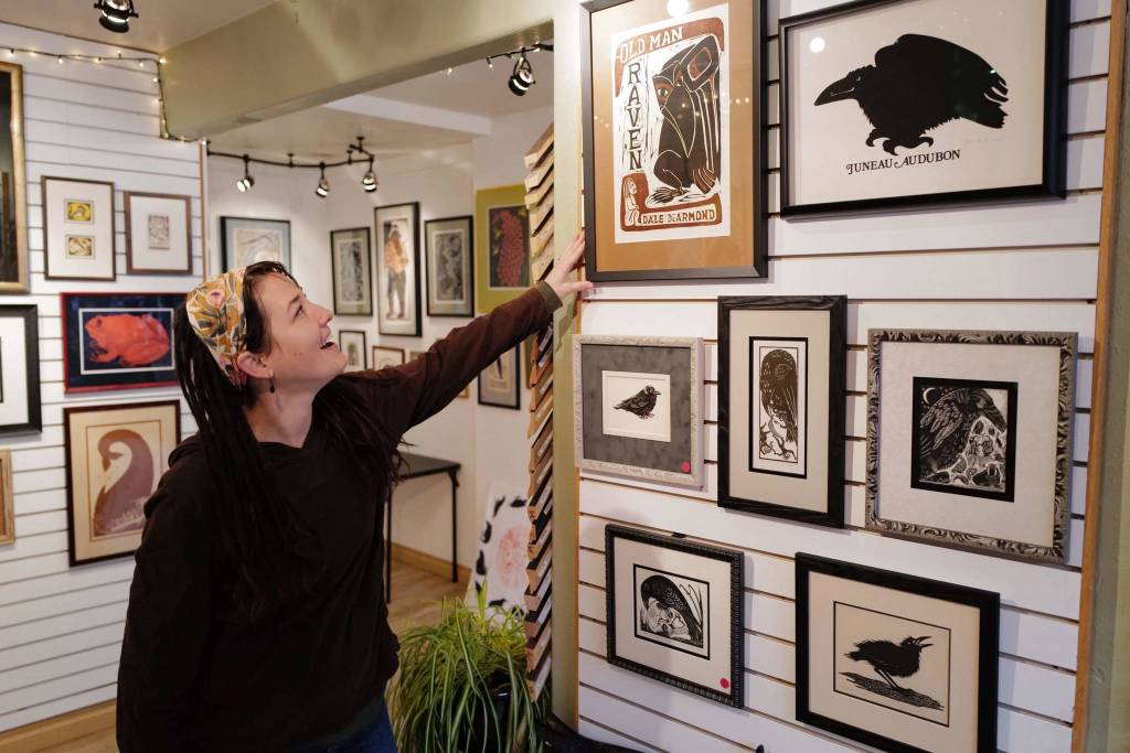 Employee Dzarae Arrowsun straightens one of Artist Dale DeArmonds artworks on display at Art Matters on Wednesday, Dec. 4, 2019. The gallery will be open during Gallery Walk this Friday. (Michael Penn | Juneau Empire)