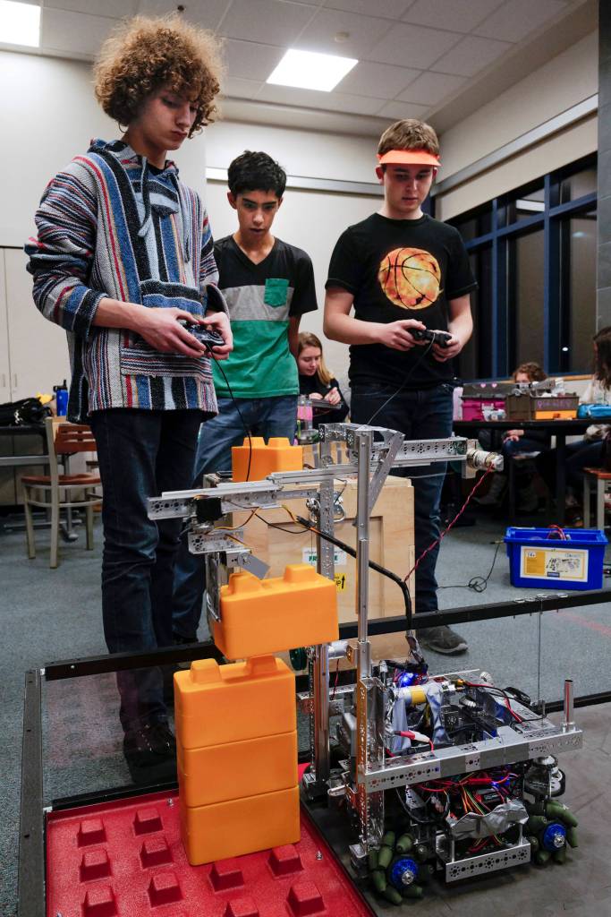 Junior Remington Wiley, left, freshman Jaman Goh, center, and junior Keelan Cunningham, of the team Chain Reaction, watch their robot stack blocks during practice for the Thunder Mountain High School robotics team at TMHS on Thursday, Dec. 5, 2019. (Michael Penn | Juneau Empire)