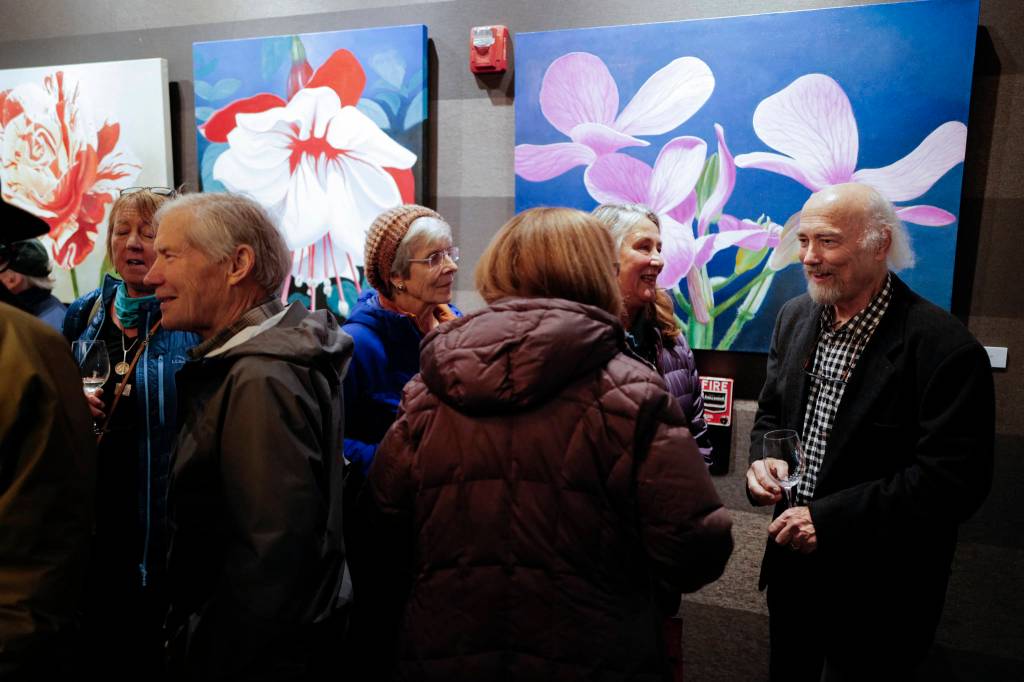 Dan DeRoux, right, talks with visitors to his Power Flowers exhibit at Salt during Gallery Walk on Friday, Dec. 6, 2019. (Michael Penn | Juneau Empire)