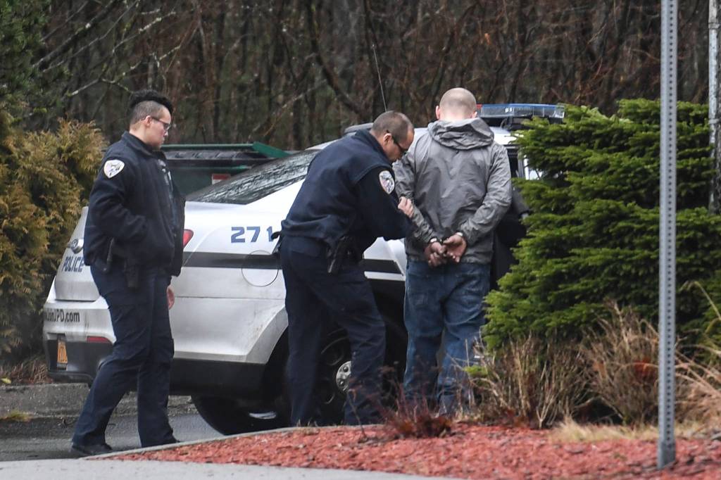Juneau Police Officer Jim Quinto, center, and CJ Warnaca put Nick Morgan into the back of a police cruiser at the Department of Transportation and Public Facilities Buildig on Channel Drive on Wednesday, Dec. 11, 2019. Morgan was a suspect involved with a stolen vehicle parked in the departments lot. (Michael Penn | Juneau Empire)