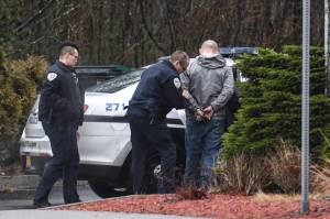 Juneau Police Officer Jim Quinto, center, and CJ Warnaca put Nick Morgan into the back of a police cruiser at the Department of Transportation and Public Facilities Buildig on Channel Drive on Wednesday, Dec. 11, 2019. Morgan was a suspect involved with a stolen vehicle parked in the departments lot. (Michael Penn | Juneau Empire)