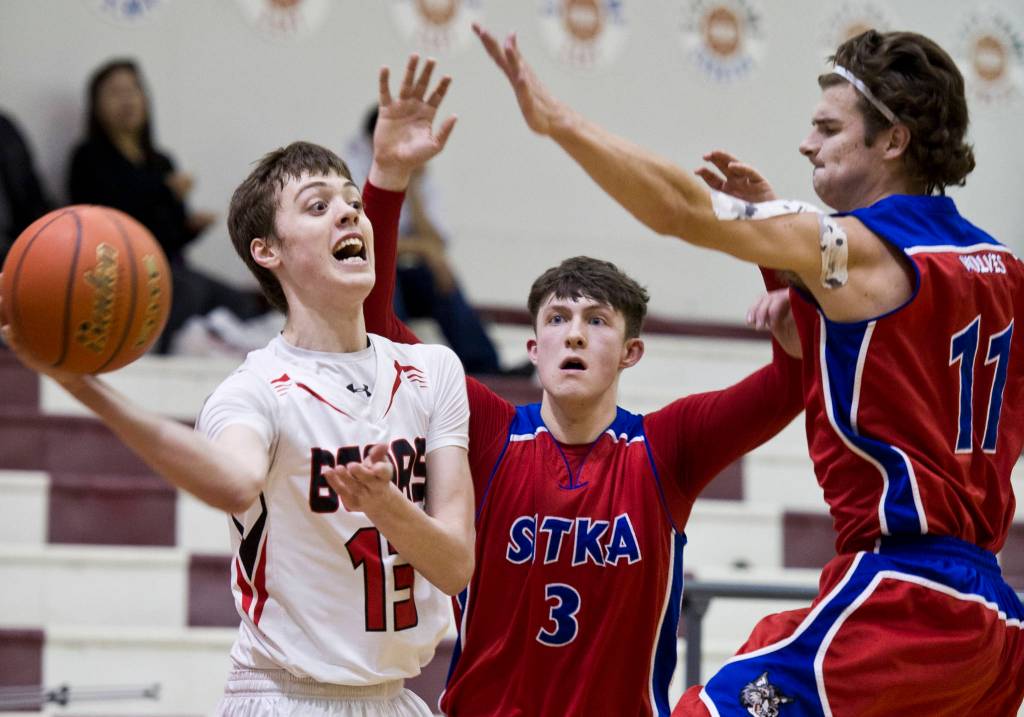Juneau-Douglas Kaleb Tompkins passes under pressure against Sitkas Branden Case, center, and Trevan Coleman at JDHS in February 2016. (Michael Penn | Juneau Empire File)
