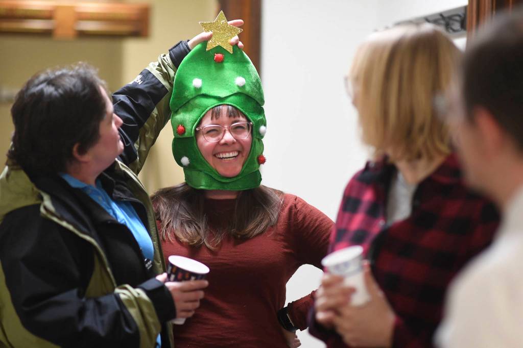 Caitlyn Ellis, a legislative aide for Rep. Andi Story, has her Christmas headgear adjusted by Rebecca Smith, left, during a legislative open house at the Capitol on Friday, Dec. 20, 2019. (Michael Penn | Juneau Empire)